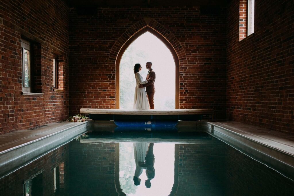 bride and groom standing by the indoor pool pennard hill farm