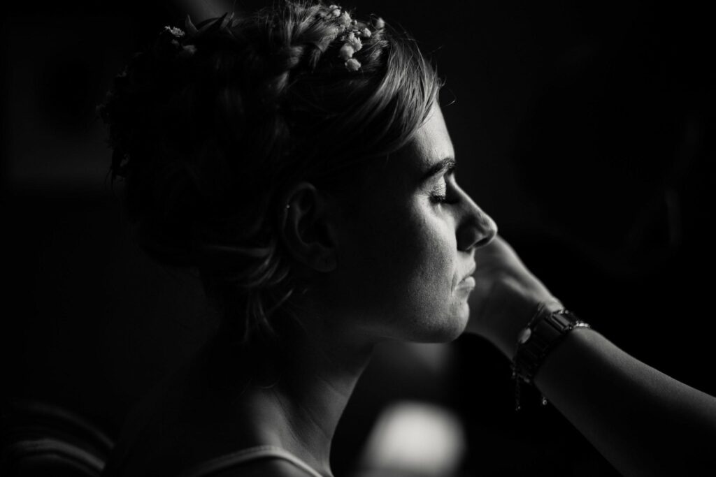 black and white profile image of bride having her makeup done