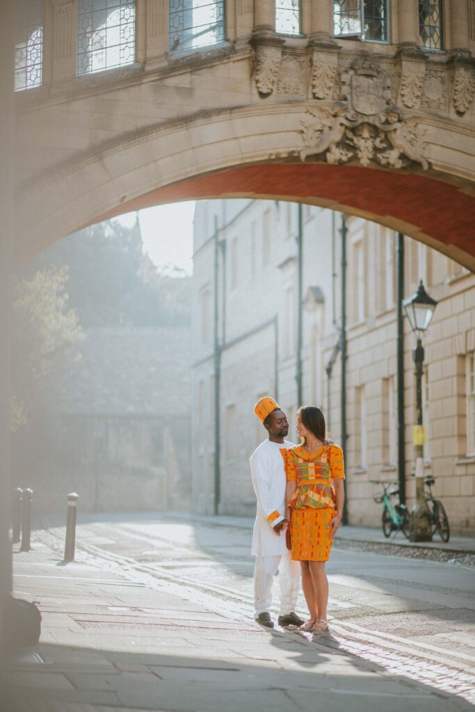 couple wearing traditional Nigerian outfits standing under the Bridge of Sighs Hertford College Oxford