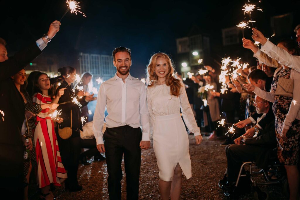 wedding guests holding sparklers and cheerfully sending away bride and groom