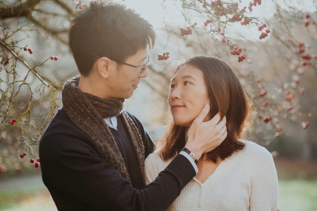 a man is gently touching women's face red berries in the backdrop Trinity College Oxford