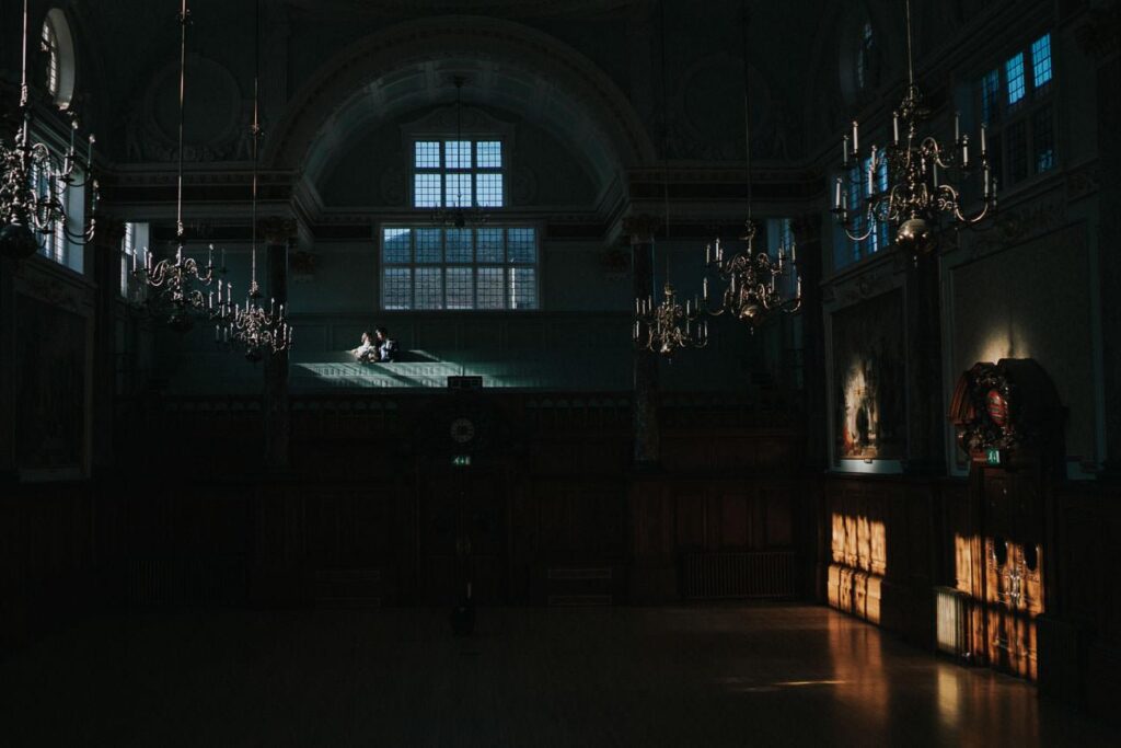 moody image of bride and groom sitting in the Chelsea Town Hall