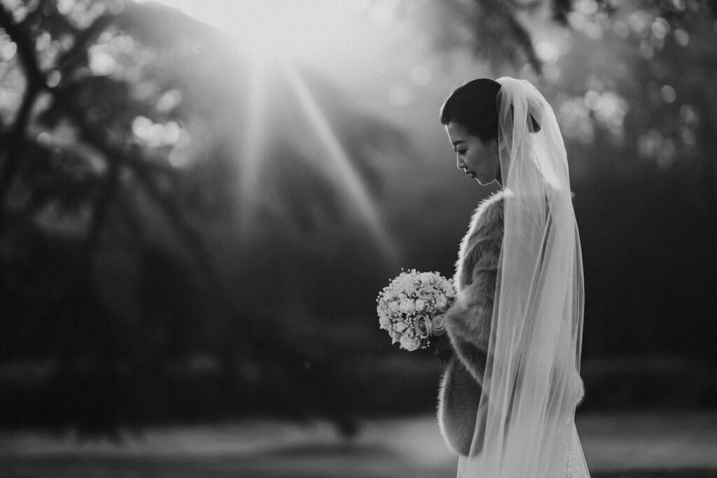 black and white image of bride in the garden. she is wearing a cape mate of fur on her shoulders
