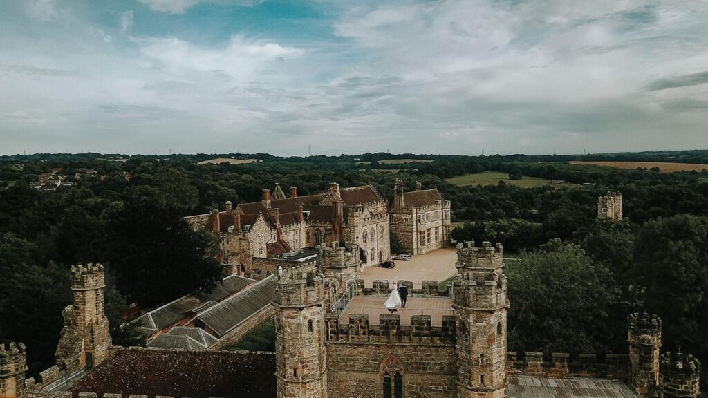 aerial image bride and groom standing on the top of battle abbey school