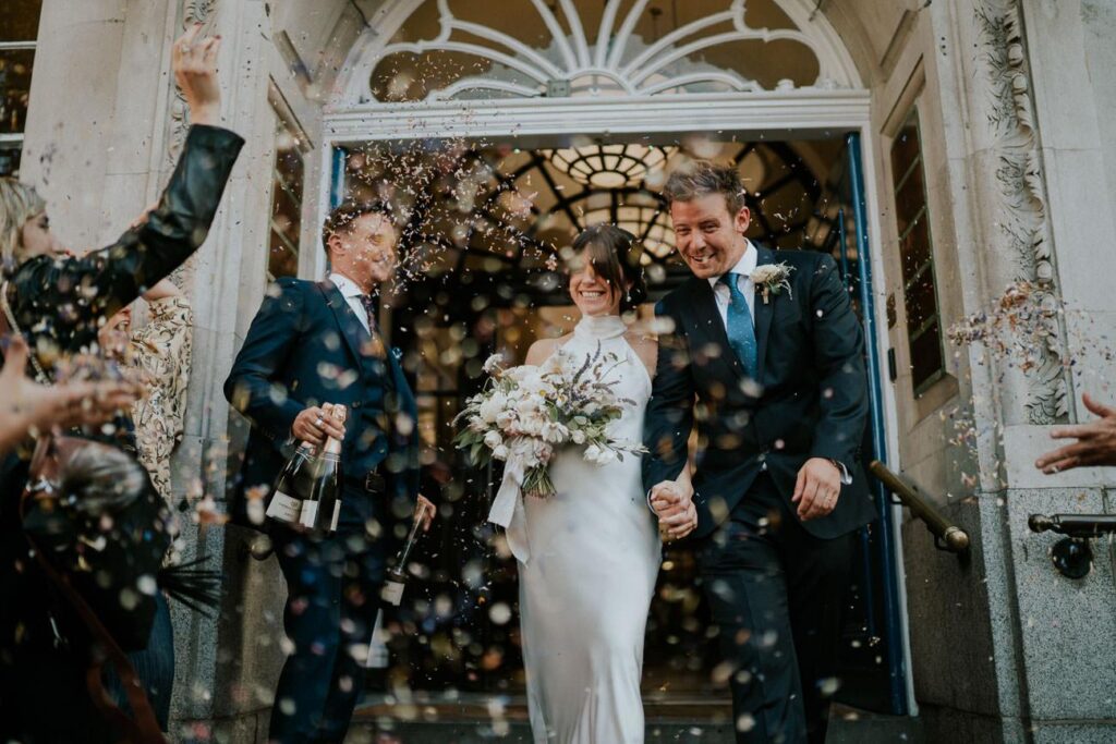 bride and groom leaving the ceremony room. Their guests throwing confetti in the air to celebrate the moment