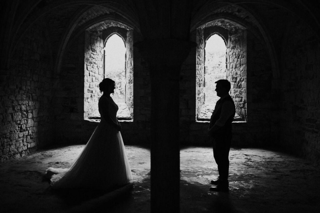 black and white moody image of bride and groom who are facing each other