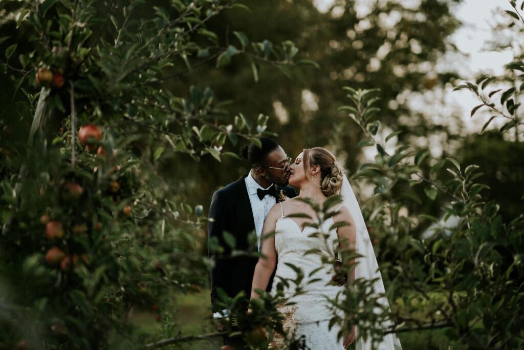 bride and groom kissing in the apple orchard