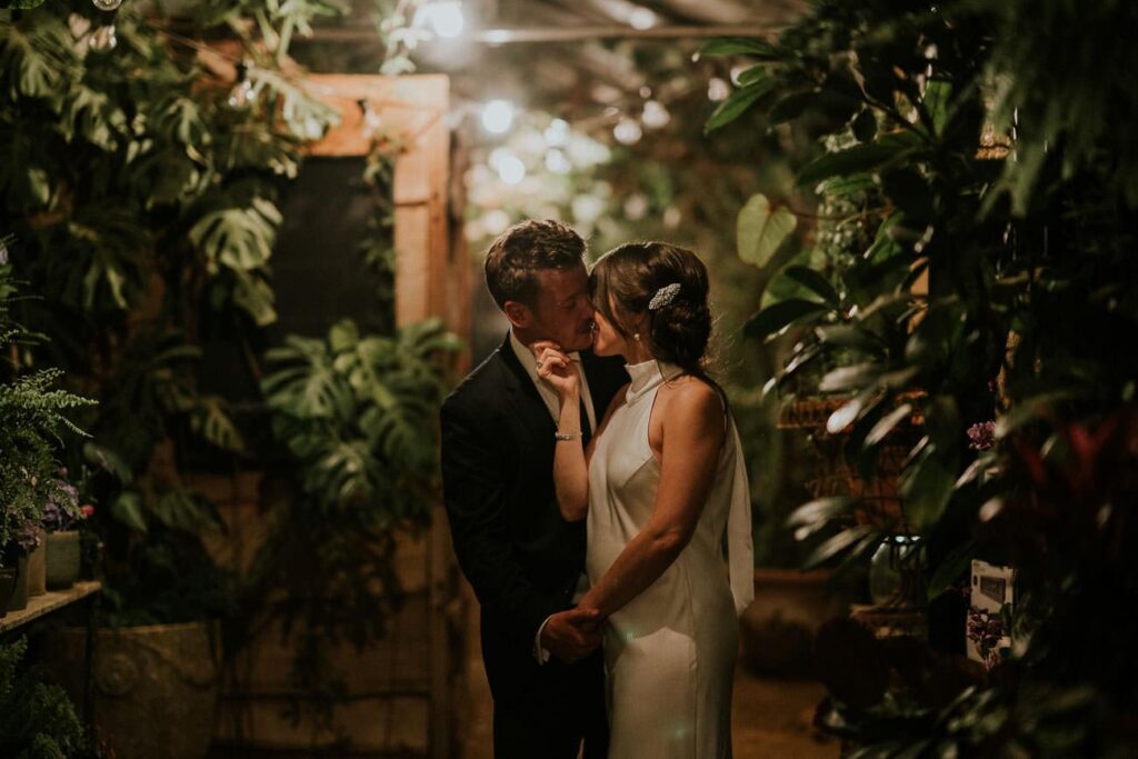 bride and groom kissing in the greenhouse