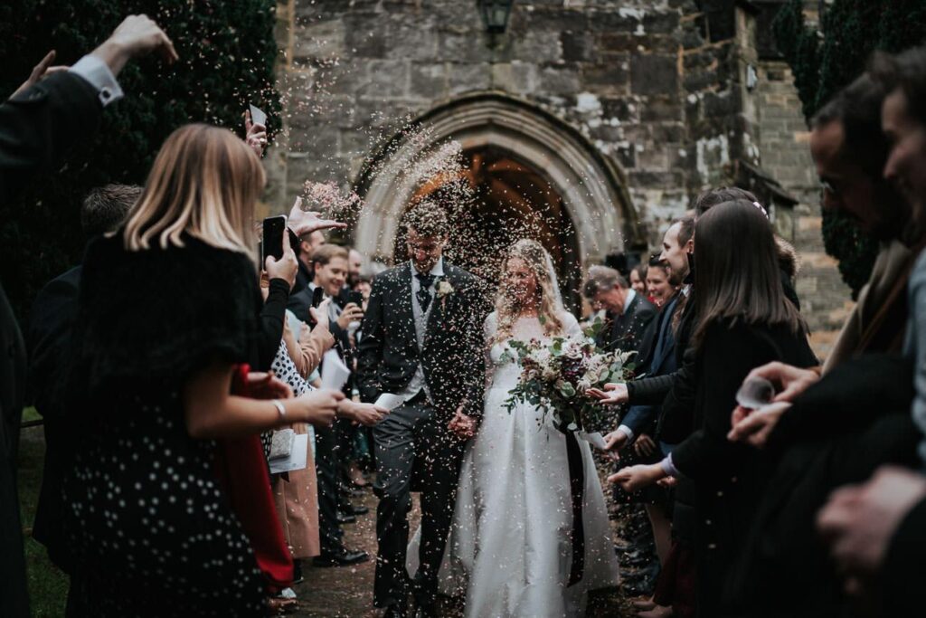 bride and groom passing by the confetti ling. There is so much confetti in the air that their faces are entirely covered