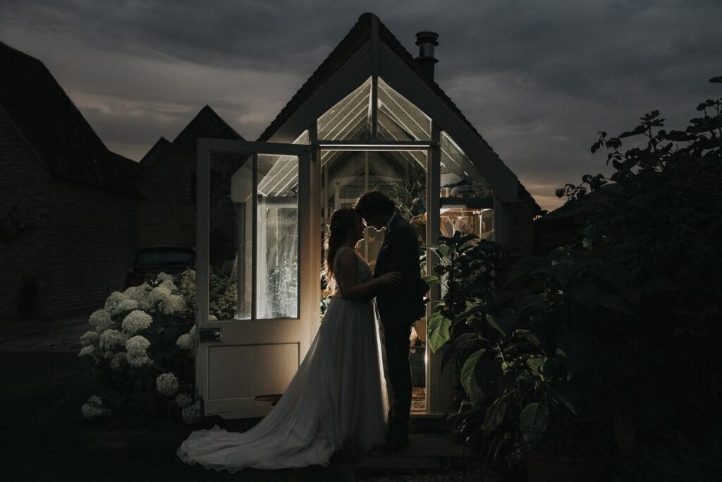 a sunset photo of newlyweds facing each other on the green house front