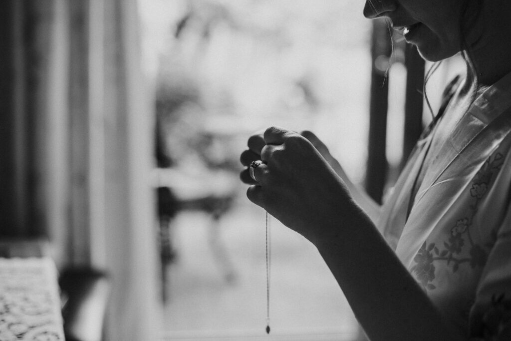 black and white photograph of bride putting her neckless on