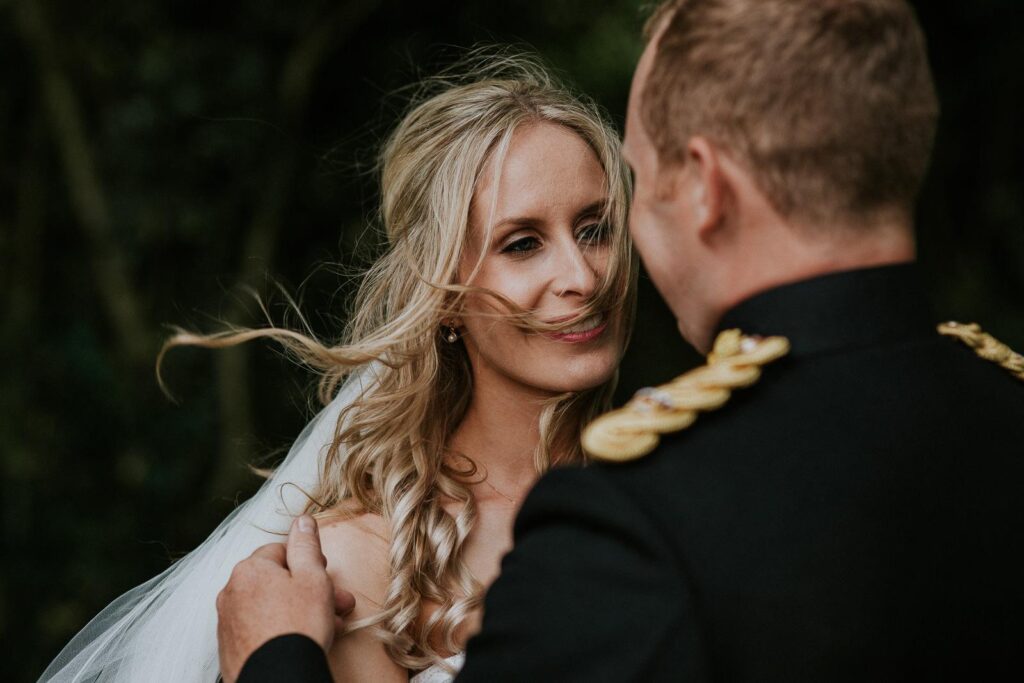 bride is lovingly looking into her grooms eyes. A wind is plying with her hair
