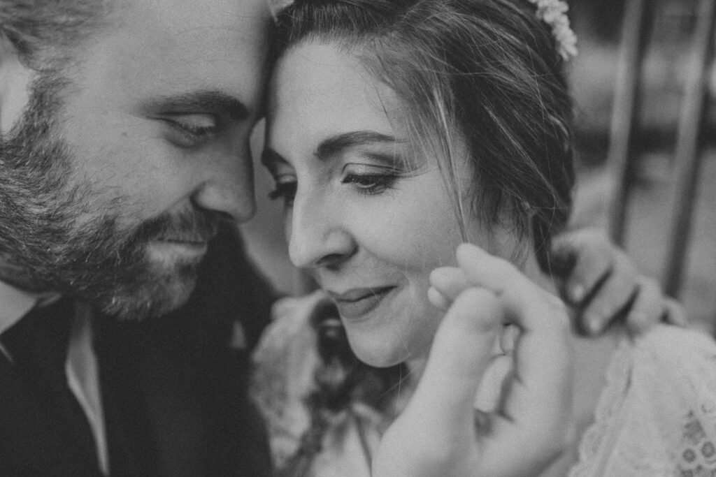 grainy black and white closeup image of newlyweds faces. he is gently touching her face