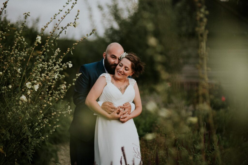 bride and groom hugging in the lovely green garden. She has her eyes closed and is softly smiling