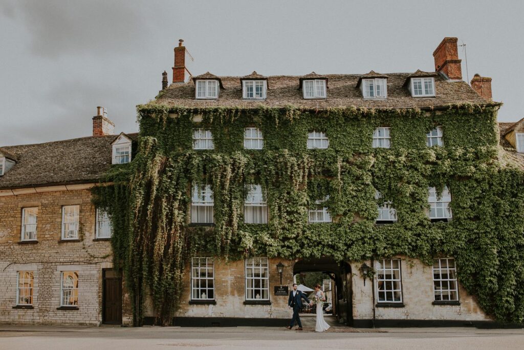 groom and bride passing by the big Edwardian building covered in ivy