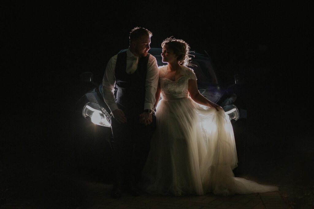 night image of bride and car sitting on the car bonnet