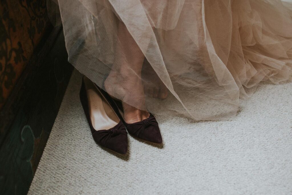 image of bride putting her burgundy wedding shoes on